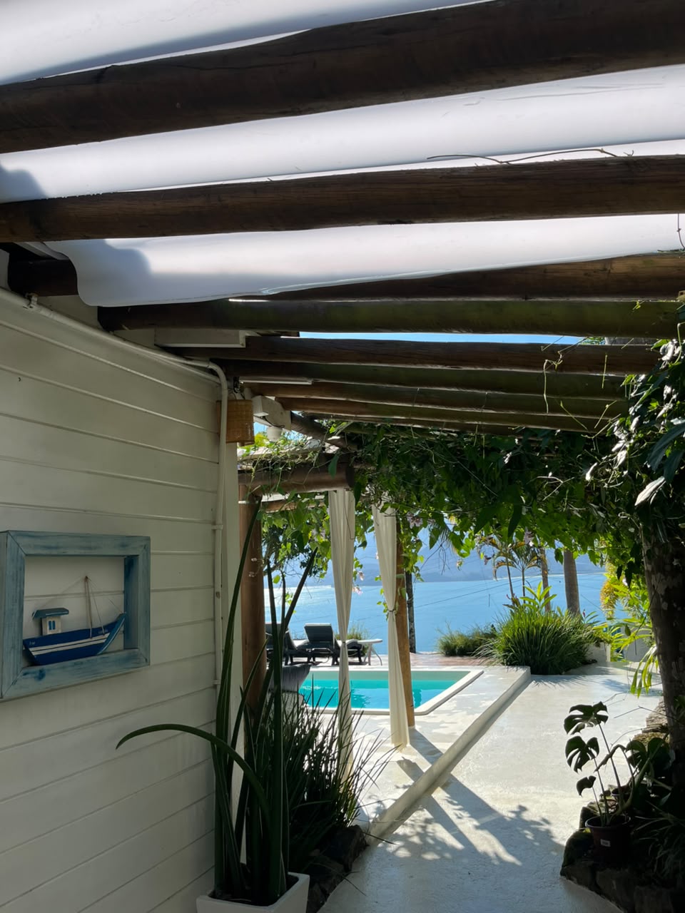 Piscina e hidro emolduradas por folhagens, vista para a baía